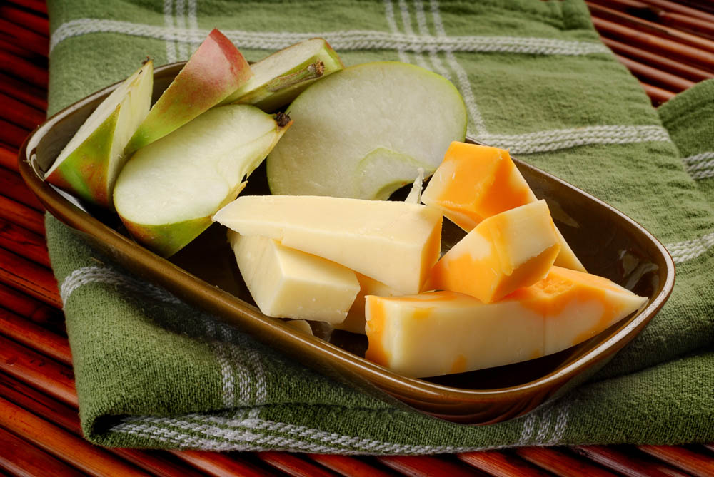 Close-up image of cheese with apples on the side