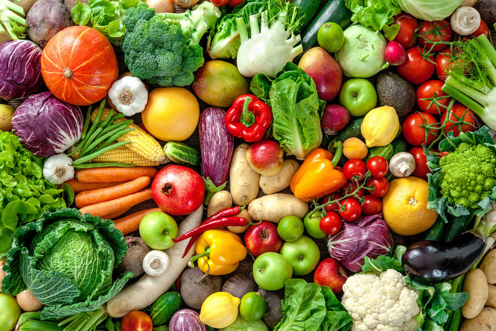 A colorful assortment of fresh fruits and vegetables, including apples, peppers, lettuce, tomatoes, and broccoli, arranged closely together.