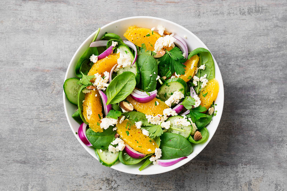 Fresh spinach salad with oranges, feta (ricotta) cheese, red onion and pine nuts .