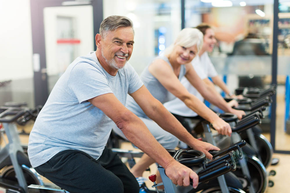 Confident seniors on exercise bikes in spinning class at gym