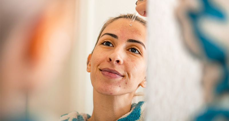 A close-up of a smiling woman looking into a mirror, radiating positivity and self-reflection.