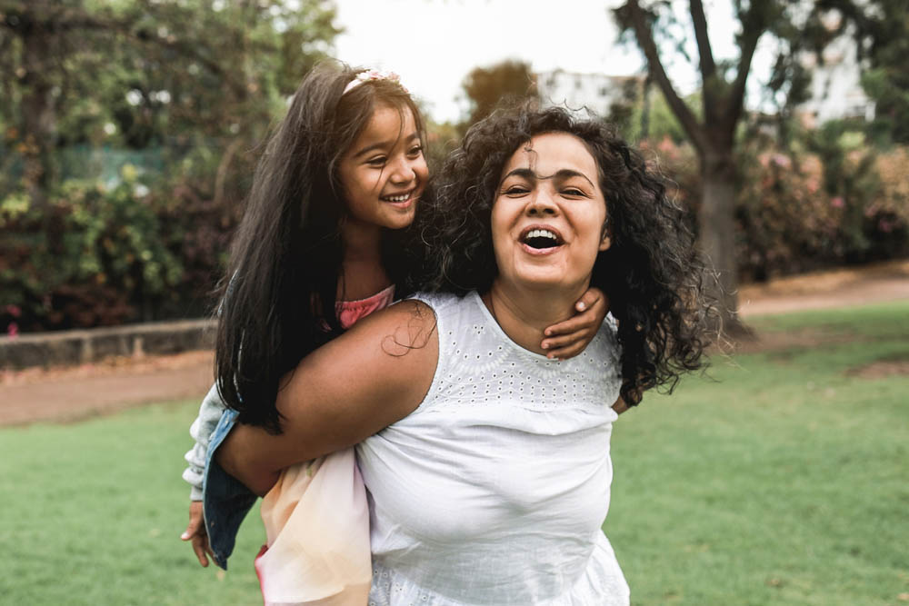 Happy indian mother having fun with her daughter outdoor - Soft focus on mom face
