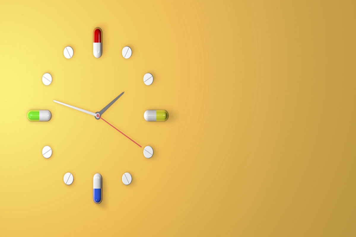 Clock made of pills and capsules on a yellow background, symbolizing medication schedule