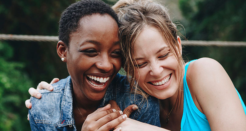 2 female friends smiling while holding each other