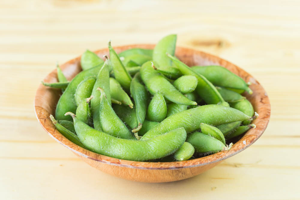 Fresh steamed edamame sprinkled with sea salt on a rustic tabletop.