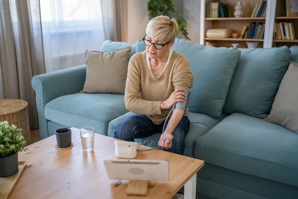 One woman senior caucasian female use blood pressure device on hand to check health results while sit at home real people health care concept