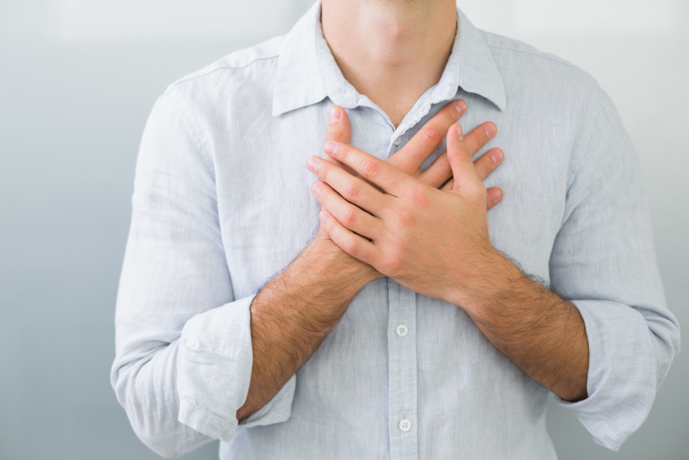 Man holding both hands over middle of chest