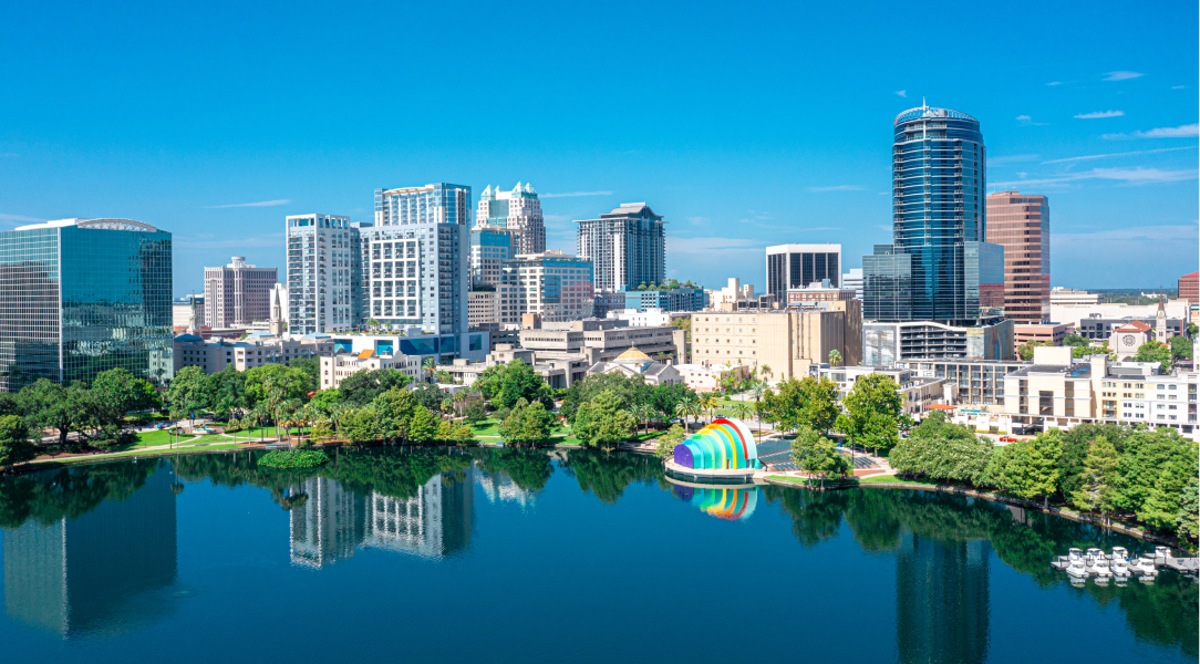 A vibrant aerial view of a city skyline, showcasing modern buildings against a clear blue sky.