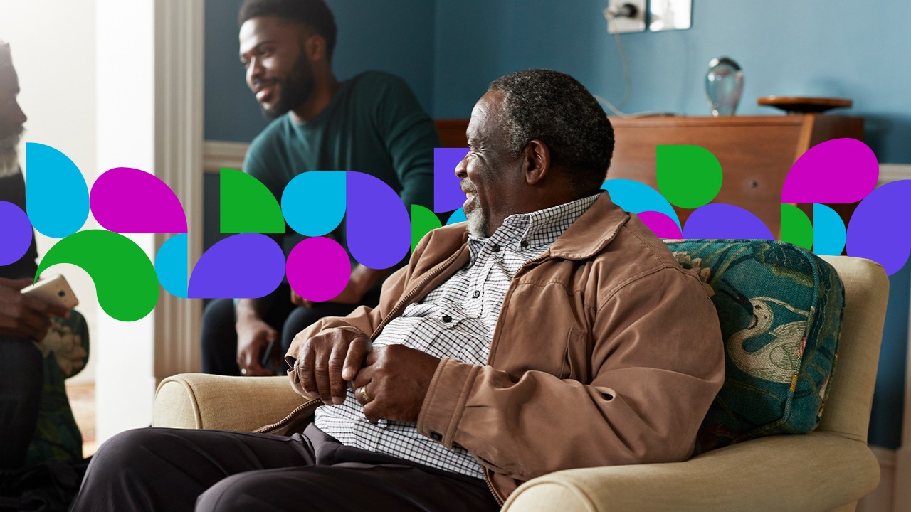 Senior man sitting in armchair talking with people