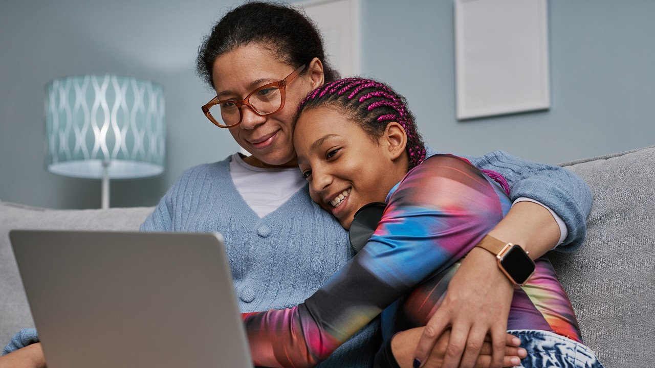 mother and daughter smiling while looking at a computer