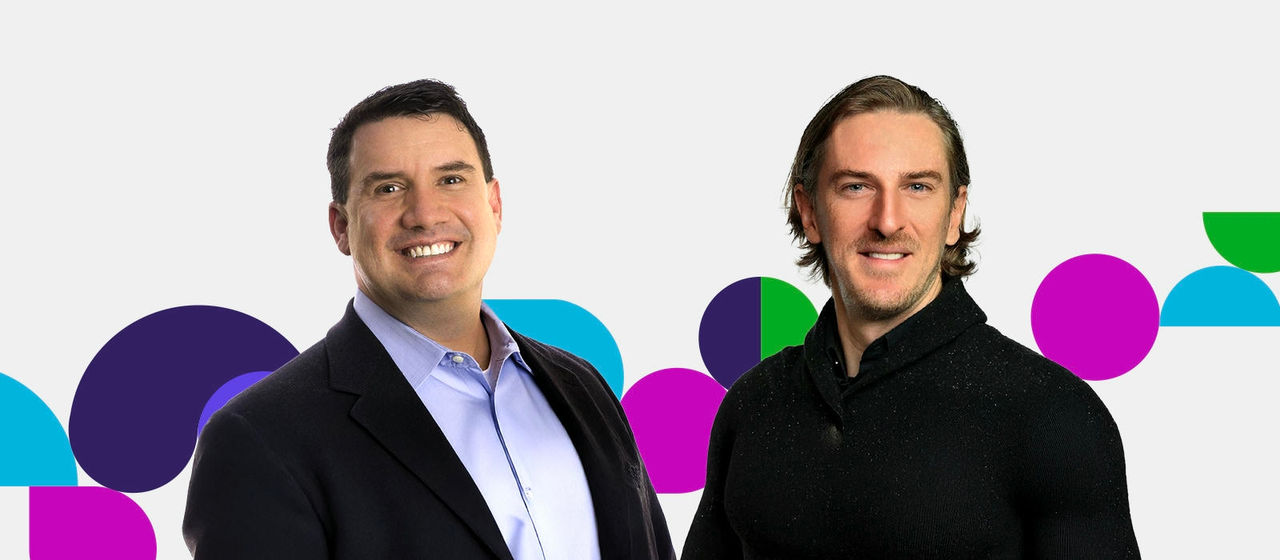 Matt Sopcich wearing a dark gray blazer over a light blue shirt, standing next to Russell DuBois, who is dressed in a black sweater. Both are posed in front of a vibrant background featuring overlapping purple, blue, green, and pink shapes.