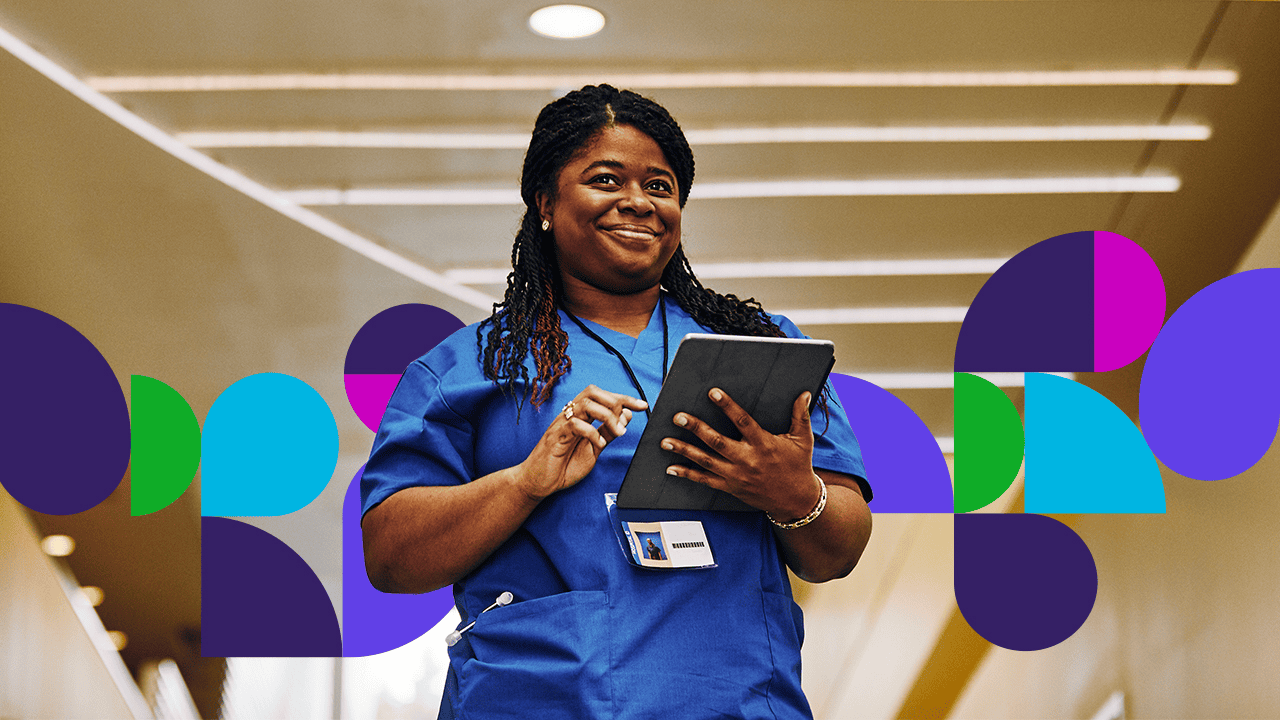 Medical professional smiling holding laptop in hallway