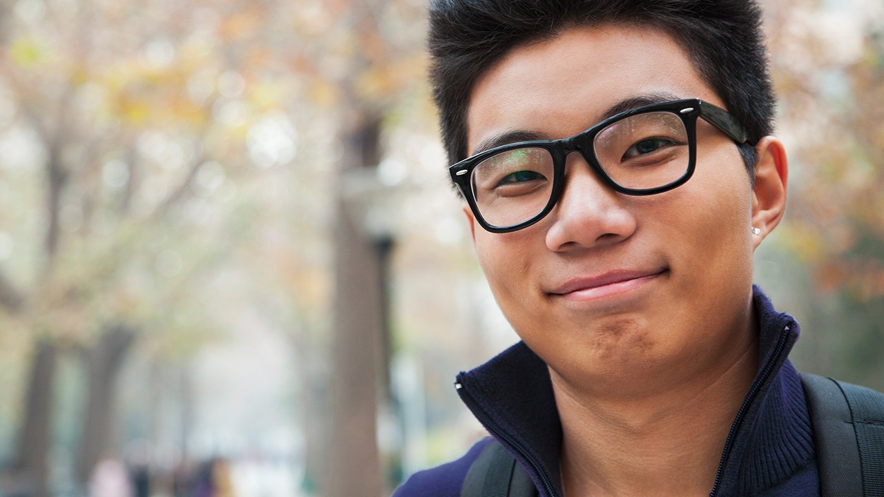A young asian man wearing glasses smiling