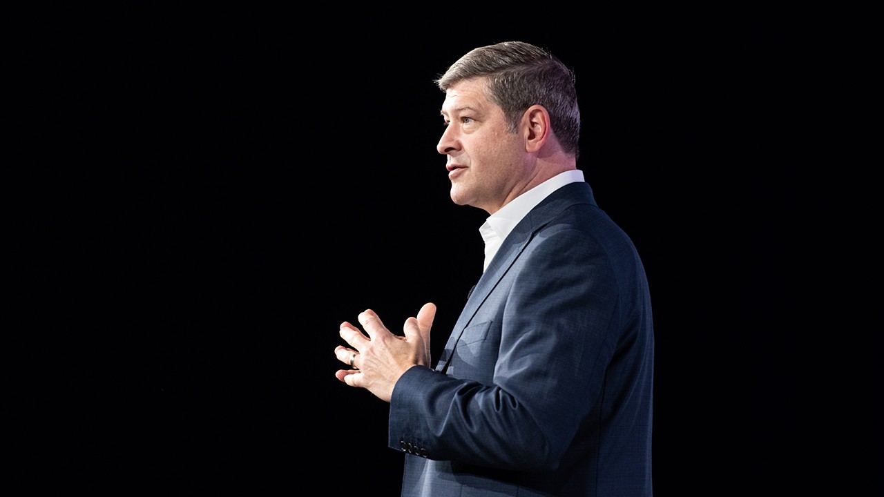 CEO Chuck Divita standing in front of a black background.