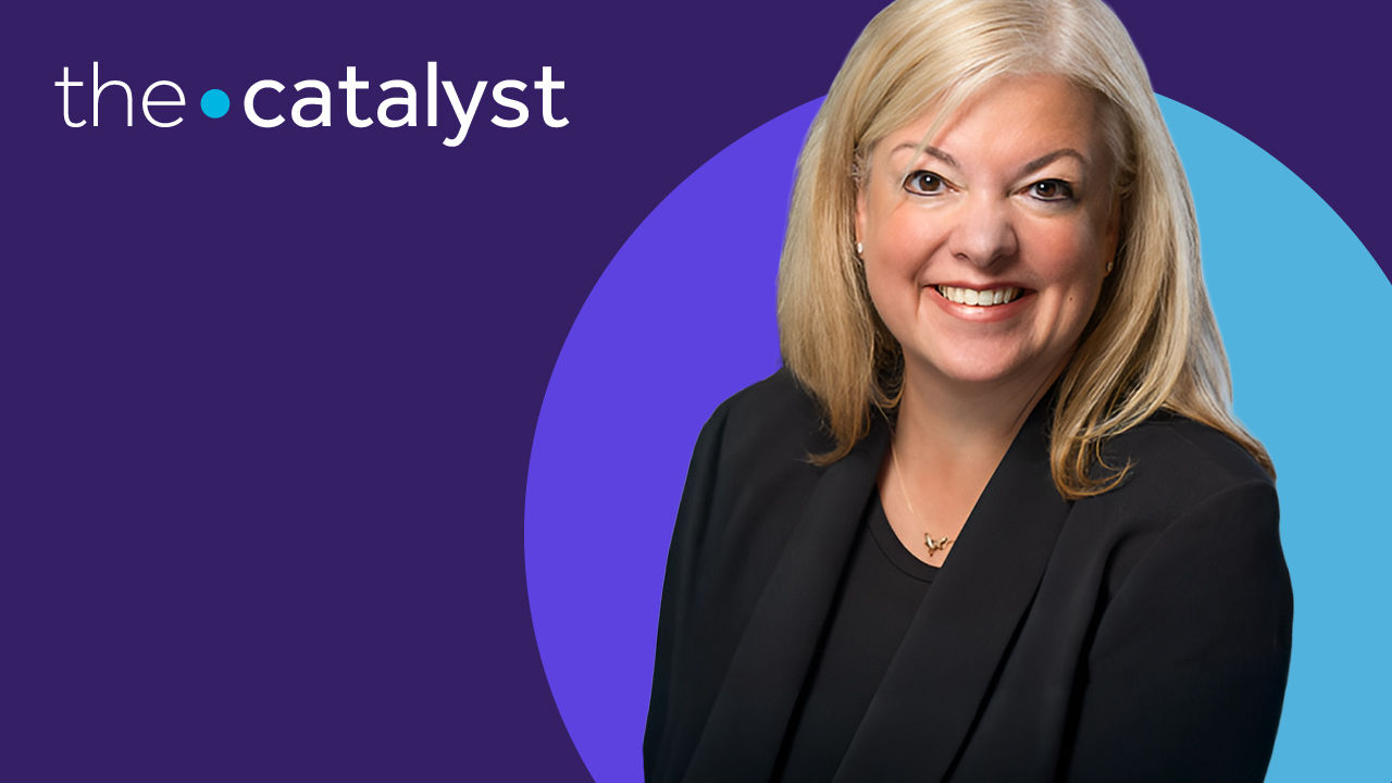 Kristen Moody wearing a dark blazer with a vibrant purple and blue background.