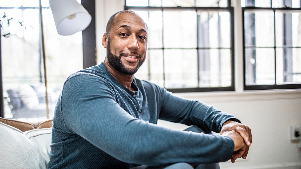 African American man sitting on couch looking at camera and smiling