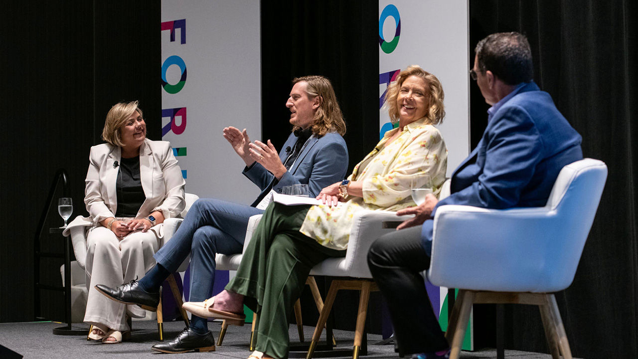 Four professionals seated on stage chairs