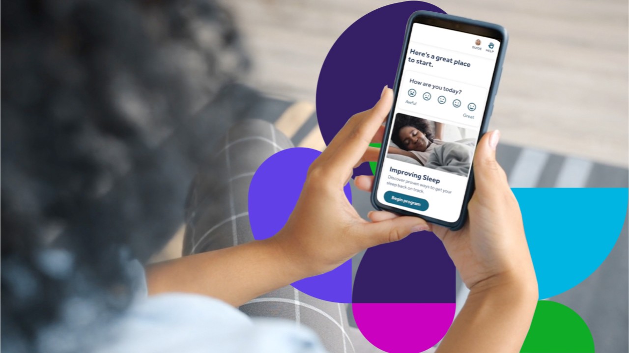 Person holding phone showing Teladoc Health app on screen