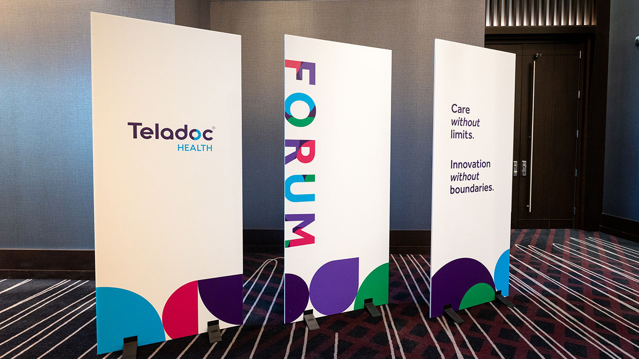 Three standing banners displayed at a Teladoc Health event. The first banner shows the Teladoc Health logo, the middle banner displays the word 'FORUM' in bold colorful letters, and the third banner reads 'Care without limits. Innovation without boundaries.' with abstract shapes at the bottom.