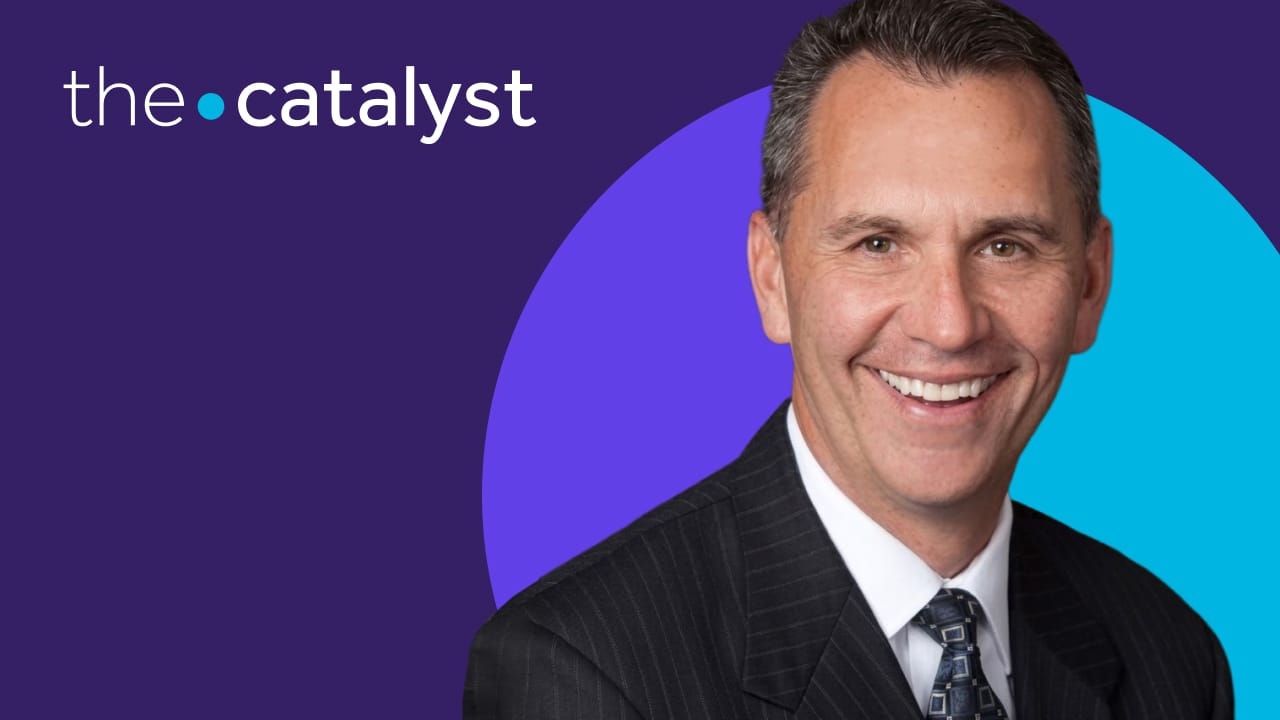Professional portrait of Pat Sir in a suit on a purple background, branded “The Catalyst.