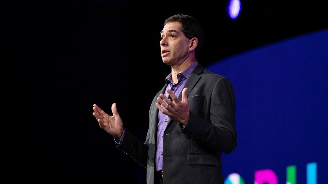 Ethan Burke standing in front of a background with a large Forum logo