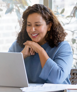 Woman smiling while looking at a laptop during a video call. 