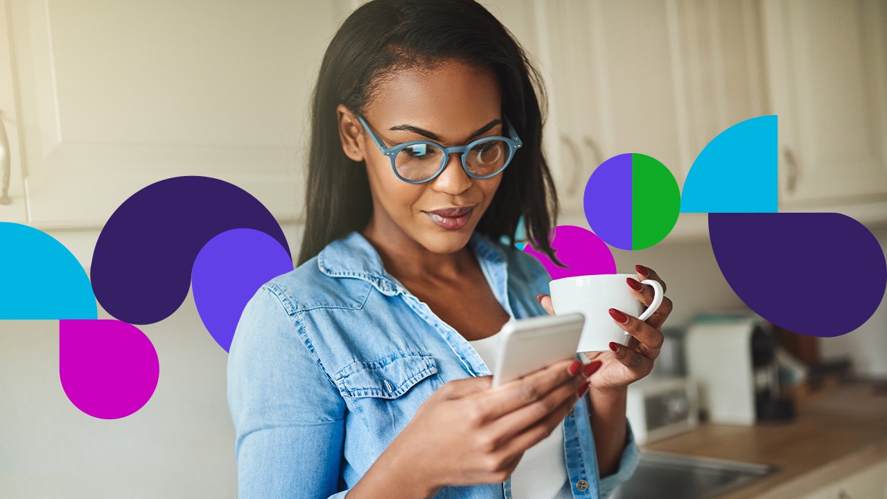 Woman with glasses holding coffee cup looking at cell phone