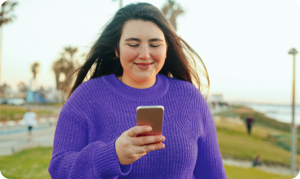 woman standing and smiling at her phone