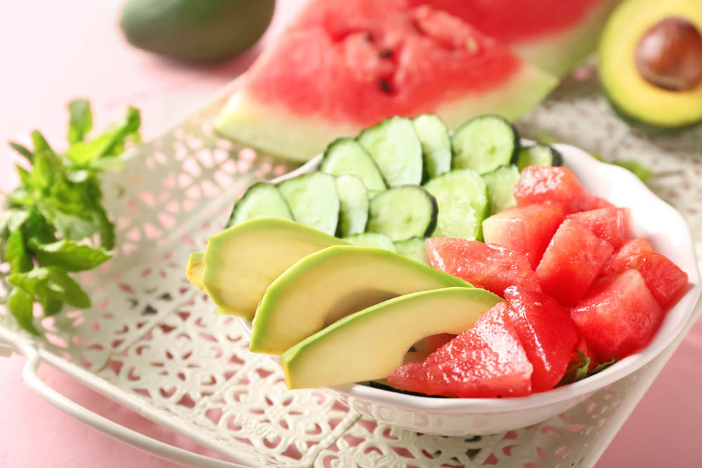 Tasty salad with watermelon, feta and vegetables in bowl on vintage tray
