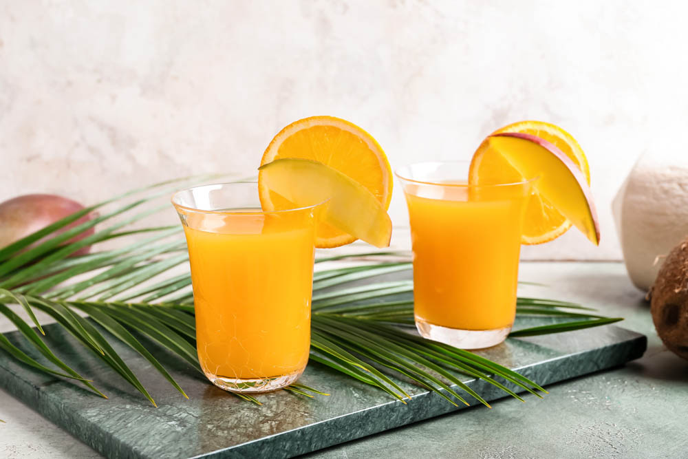 Glasses of tasty mango margarita on color background
