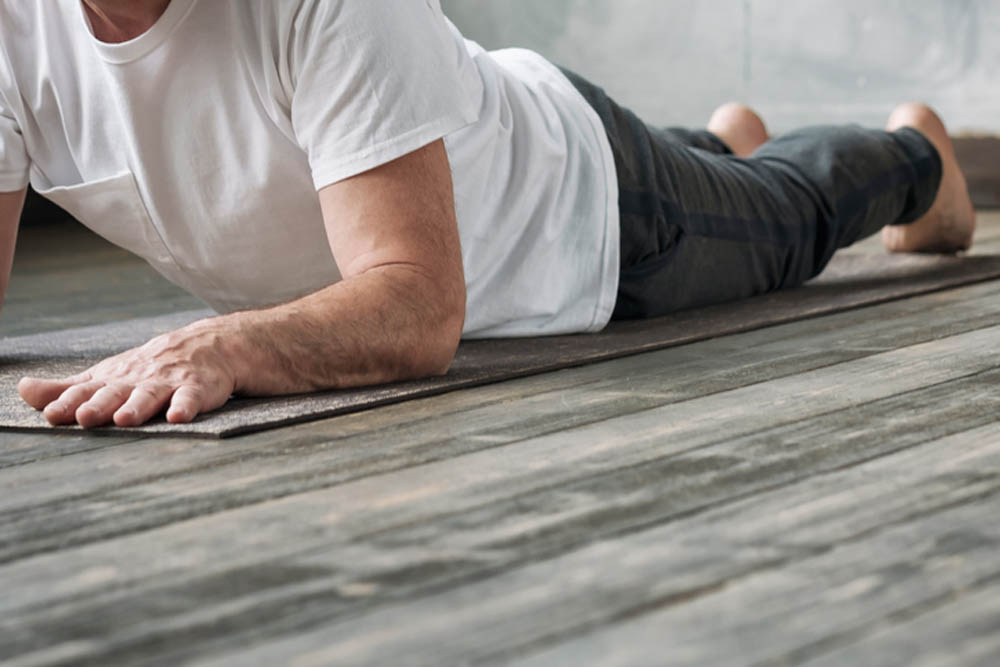 Yoga man in Cobra or sphinx pose bhujangasana variation in the gym. No face view.