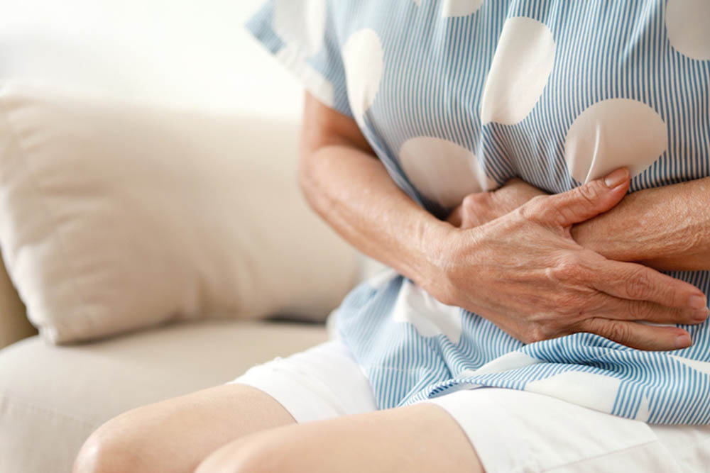 Woman holding stomach with both hands
