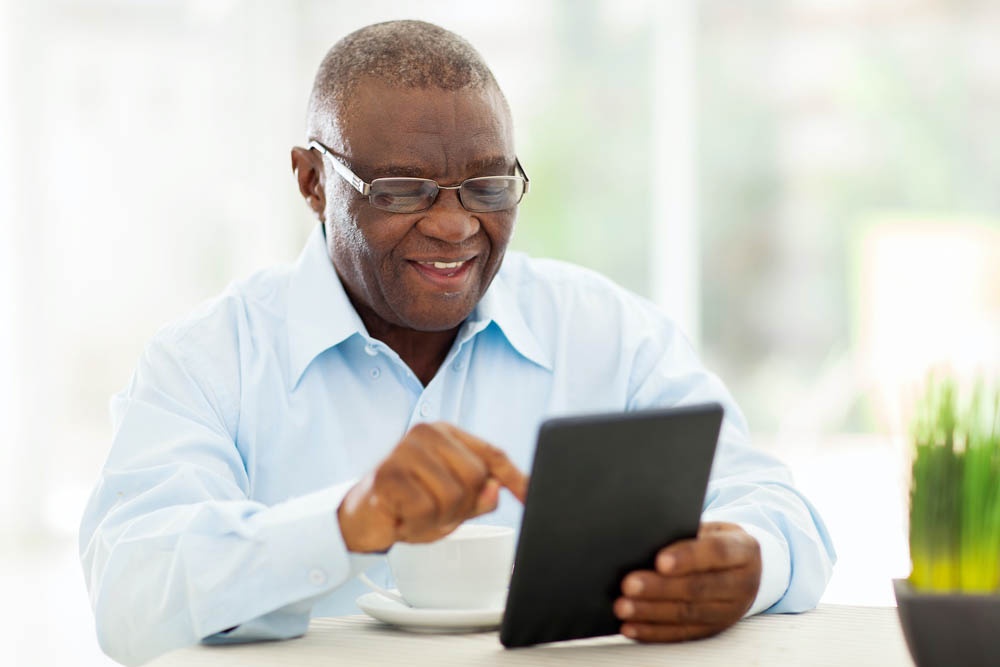 cheerful senior african american man using tablet computer at home