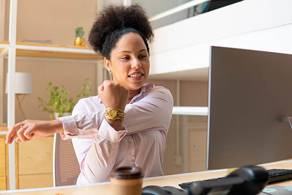 Happy black business woman stretching arms in workstation. health, ergonomics, wellbeing concept.