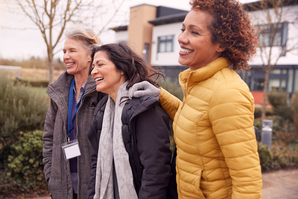 Group Of Smiling Female Mature Students Walking Outside College Building