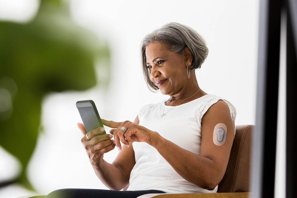 Attractive senior African American woman smiles while video chatting with her grandchildren.