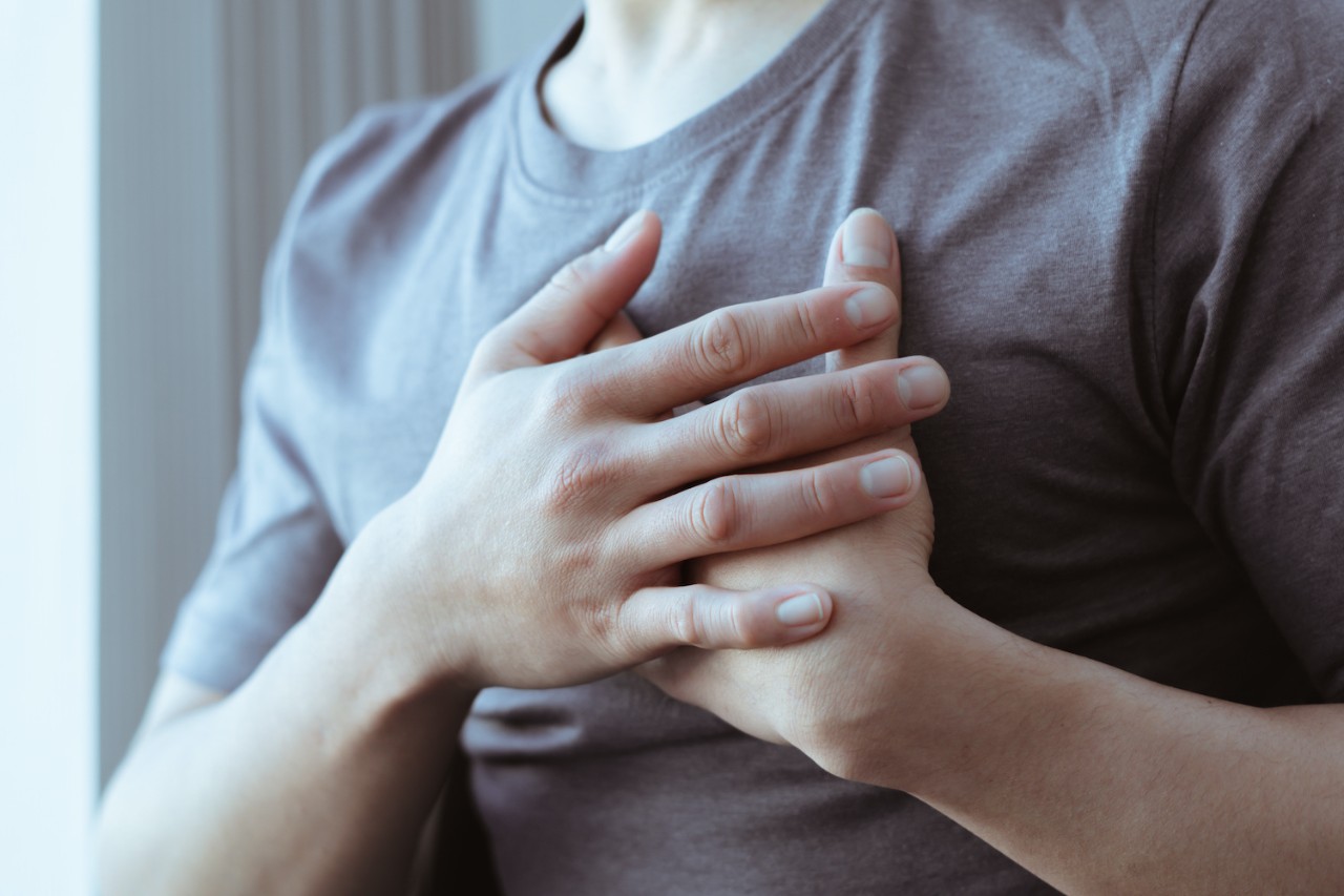 Person in a gray shirt with both hands over their heart. 