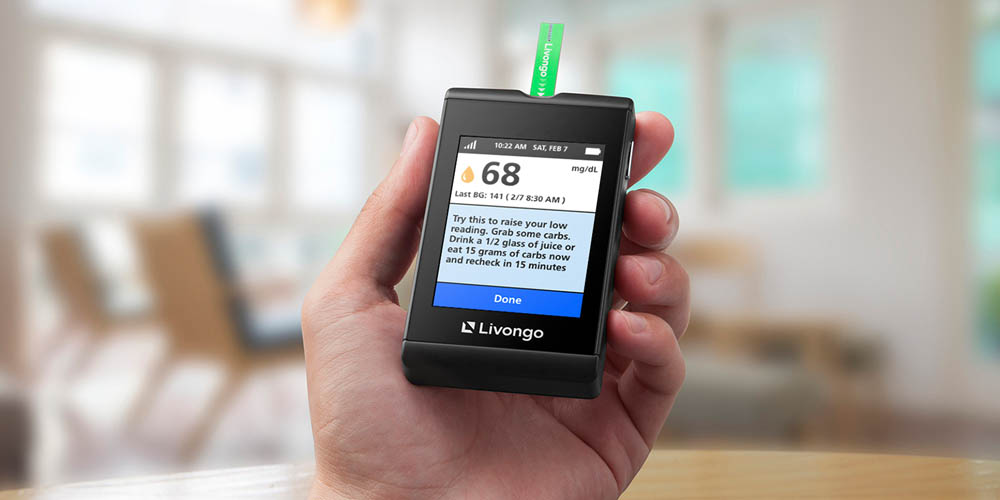 Hand holding a Livongo blood glucose meter displaying a reading.