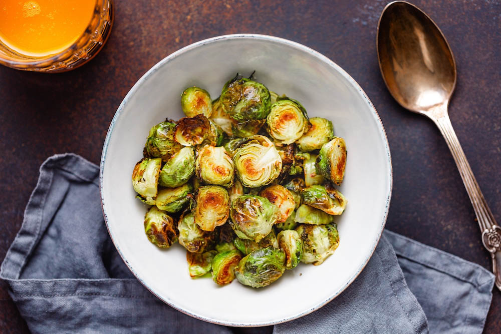 Top view of a ceramic bowl with roasted brussel sprouts on a table. The concept of healthy vegetarian eating.