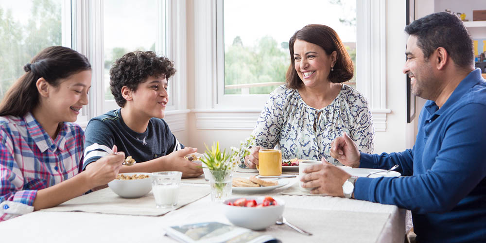 A family sitting at a dining table enjoying a meal together.