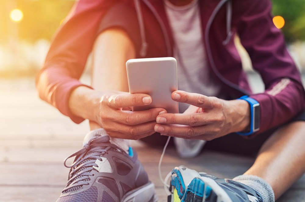 Person in workout clothes and shoes looking at mobile phone.