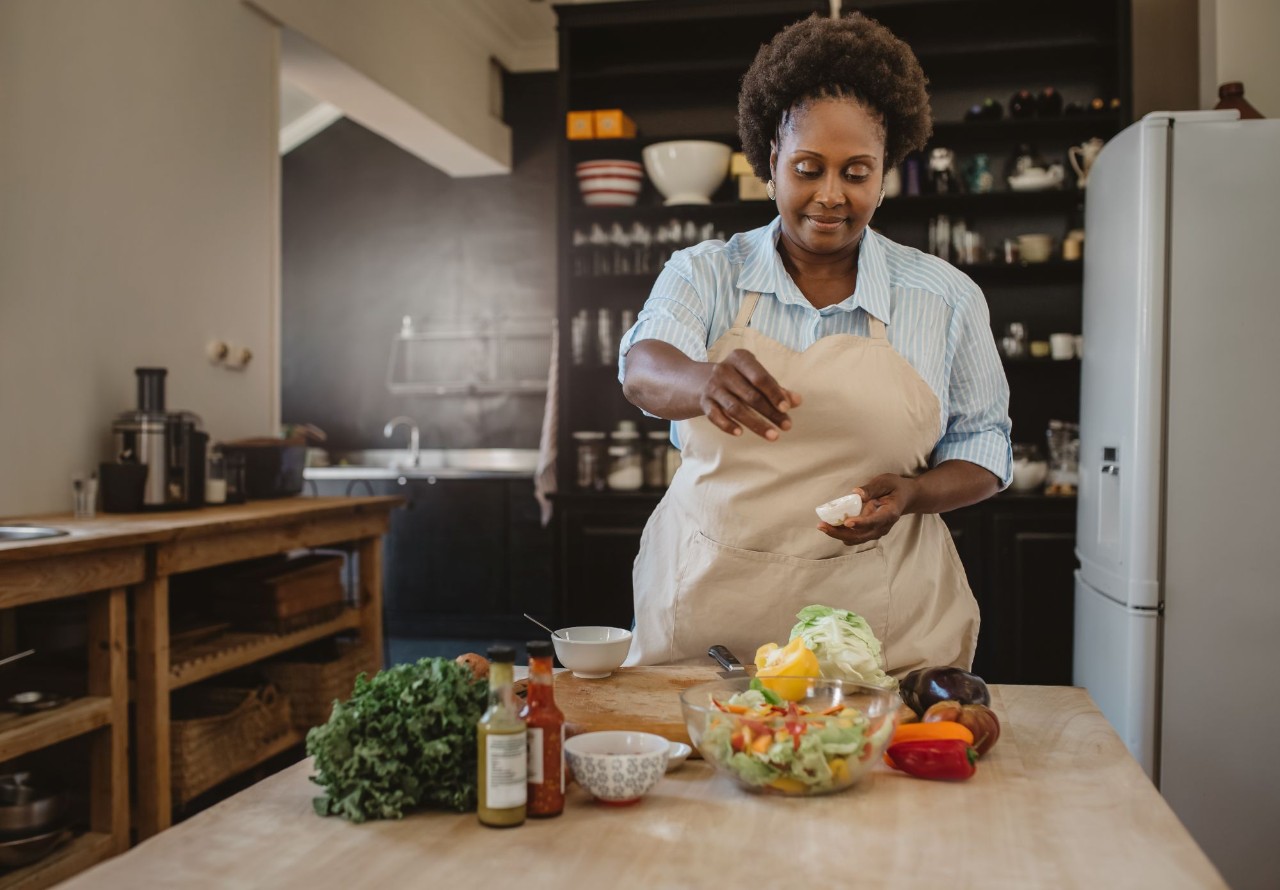 Woman in kitchen sprinkling salt on food