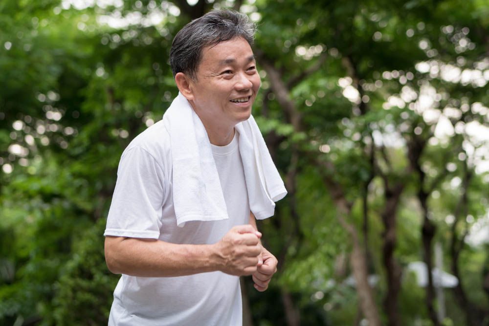 happy smiling old man running in nature park outdoor scene, middle aged to senior age range
